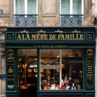 Façade d’un immeuble parisien avec commerces au rez-de-chaussée et balcons à l’étage.