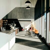Intérieur vide d’un café contemporain avec comptoir, tables et baies vitrées.