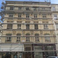 Façade d’un immeuble lyonnais entourée d’un échafaudage pendant un ravalement.
