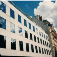 Façade vitrée d’un immeuble de bureaux à Paris sous un ciel bleu.