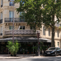 Façade d’un immeuble d’angle parisien avec un fleuriste au rez-de-chaussée.